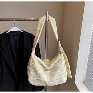 Detail view of the yellow quilted puffer shoulder bag showing texture and logo
