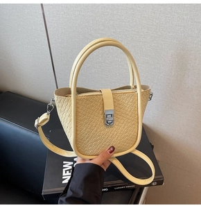 Détail d'un sac seau jaune clair avec texture tressée, fermoir argenté et bandoulière