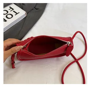 Vue de dessus du sac selle rouge à motif litchi avec fermeture éclair et nœud tressé