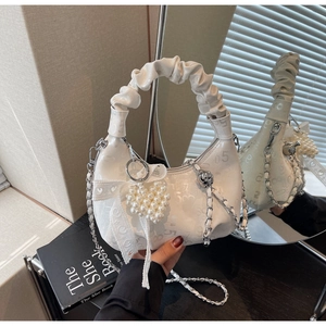Detail of white pleated hobo bag with pearl heart charm and lace bow decoration