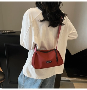 Détail d'un sac bandoulière rouge avec large sangle porté sur le dos par un mannequin