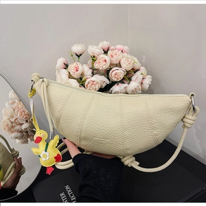 Detail of beige crescent bag featuring lychee texture leather and a cute duck pendant