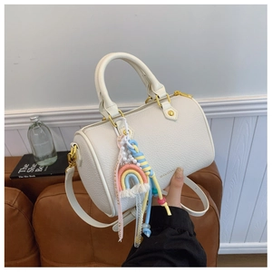 Close-up of cream Boston bag with lychee texture and Love Is Eternal woven charm