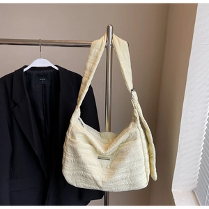 Detail of cream quilted tote bag showing ruffled texture and silver metal buckle