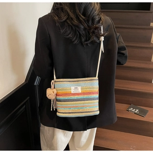 Detail of colorful striped woven bucket bag with rope strap and cute bear charm