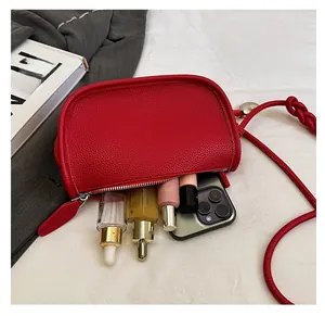 Détail intérieur d'un sac selle rouge contenant smartphone et divers cosmétiques