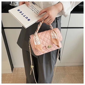 Detailed view of pink quilted handbag with silk scarf handle and golden twist lock