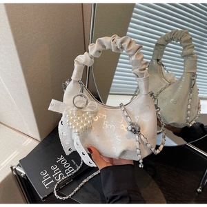 Detail view of cream crescent bag featuring pearl heart charm and lace bow decor