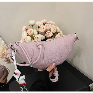 Detail of light pink lychee leather croissant bag featuring a unique knotted shoulder strap