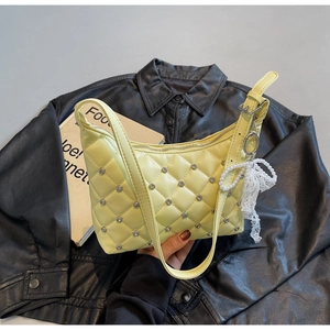 Détail d'un sac jaune matelassé avec strass argentés et pendentif noeud en perles