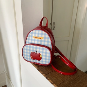 Dettaglio mini zaino in pelle verniciata rossa e tessuto a quadri blu con applicazione mela