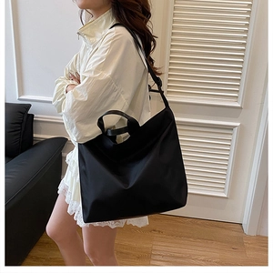 Black large capacity waterproof nylon tote bag with adjustable strap worn by a model