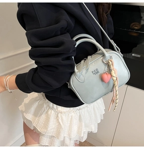 Détail du sac bandoulière bleu clair avec breloque cœur rose et sangle tissée