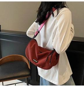 Detail of red crescent nylon crossbody bag with black adjustable strap and logo