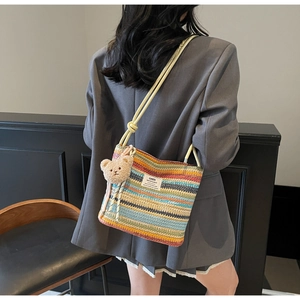 Detailed side view of multi-color woven straw bucket bag with cute plush bear pendant