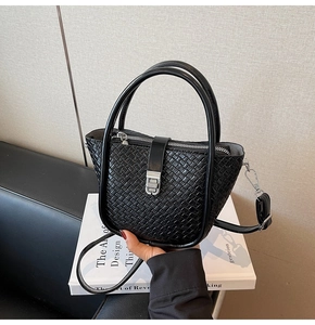 Detailed close-up of a black woven texture bucket bag with metallic zipper and twist lock