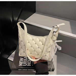 Vue détaillée d'un sac hobo matelassé crème avec strass et breloque nœud en perles