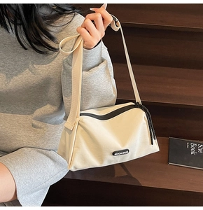 Détail du sac bandoulière en toile beige avec large sangle sur des escaliers