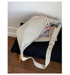 Close-up of beige nylon crossbody bag with silver zipper and heart pendant detail