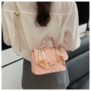 Close-up of pink quilted crossbody bag featuring golden chain and bear print silk scarf