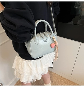 Détail d'un sac à main en cuir bleu clair avec logo Pan Tor et pendentif cœur
