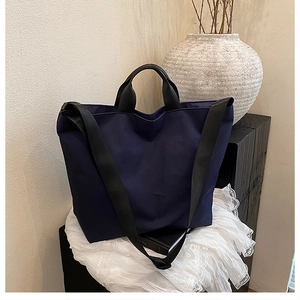 Detail of navy nylon tote bag with reinforced handles and adjustable strap on lace cloth
