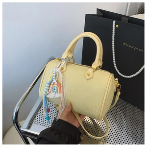 Detail of yellow lychee grain Boston bag with rainbow and pearl charms on a display stand