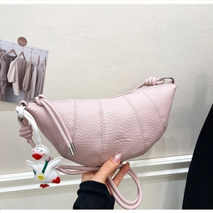 Detail view of pink leather croissant bag with knotted strap and small duck charm