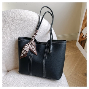 Close-up of black pebble leather tote with contrast white stitching and decorative silk scarf