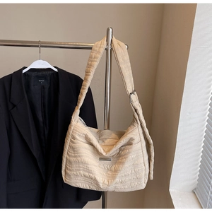 Detail of cream quilted bubble fabric texture and silver metal buckle on tote bag
