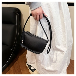 Détail d'un sac selle en cuir grainé noir avec fermeture éclair argentée et bandoulière