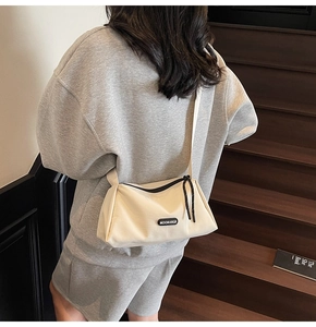 Détail du sac bandoulière en nylon blanc avec large sangle porté par un mannequin