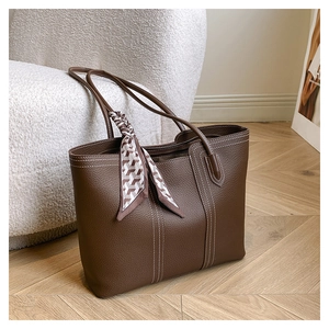 Detail of dark brown leather tote with white stitching and decorative handle scarf