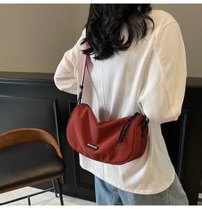 Red half-moon crossbody bag with pink strap and Moonlersa logo worn by a model