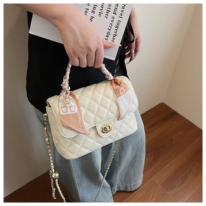 Close-up of quilted white leather box bag with gold clasp and orange silk scarf handle