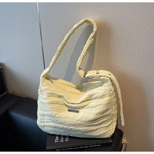 Detail of light yellow quilted tote bag showing puffy texture and metal zipper closure