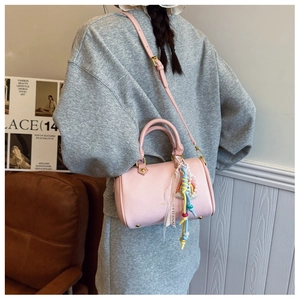 Detail of pink lychee leather boston bag with pearl rainbow charm worn as a crossbody