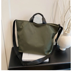 Detail of army green nylon tote bag with black handles and strap on office desk