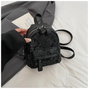 Close-up of black snake embossed mini backpack with silver hardware on grey blazer