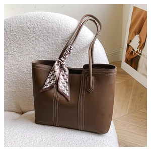 Detail of dark brown pebble leather tote with white stitching and silk scarf on handle