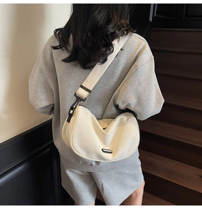 Model wearing an off-white half-moon crossbody bag with an adjustable wide strap on stairs