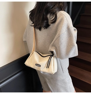 Détail d'un sac bandoulière blanc crème avec fermeture éclair noire et sangle large