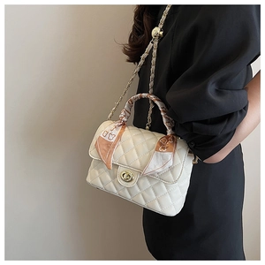 Detail of cream quilted bag featuring a golden twist lock and teddy bear print silk scarf