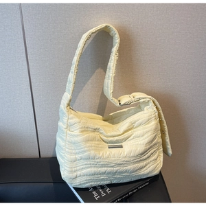 Detail of light yellow quilted tote bag with wave texture and silver metal plate detail
