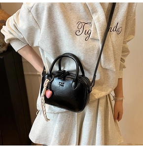 Détail du sac à main noir avec foulard en soie, breloque cœur et logo de marque PAN TOR