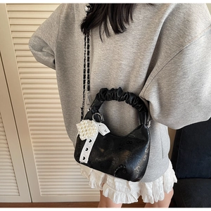 Close-up of black hobo bag with pleated handle, pearl heart charm and lace detail