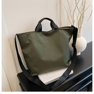 Detail view of army green nylon tote bag on a decorative shelf with a minimalist background