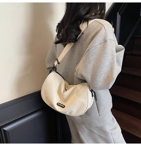 Detailed view of cream canvas crescent bag with black adjustable strap on shoulder