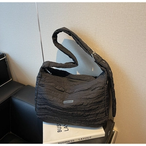 Close-up of black quilted nylon tote with pleated texture and metallic buckle detail