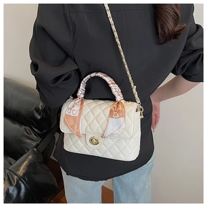 Detail of cream quilted crossbody bag with gold lock and silk scarf handle wrap